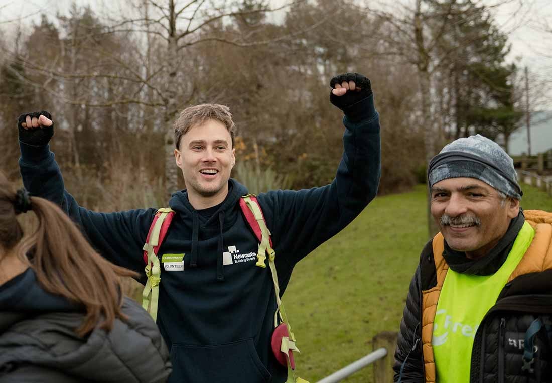 Newcastle Building Society colleagues on a charity hike, with Sean raising his arms in the air smiling. 