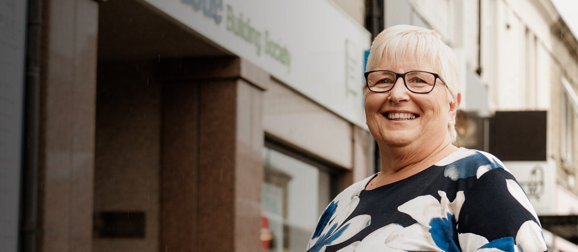 A lady who is a Newcastle Building Society customer, stood outside of the Gosforth branch smiling. 