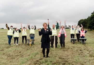 A group of people in hi-vis jackets cheer in a field