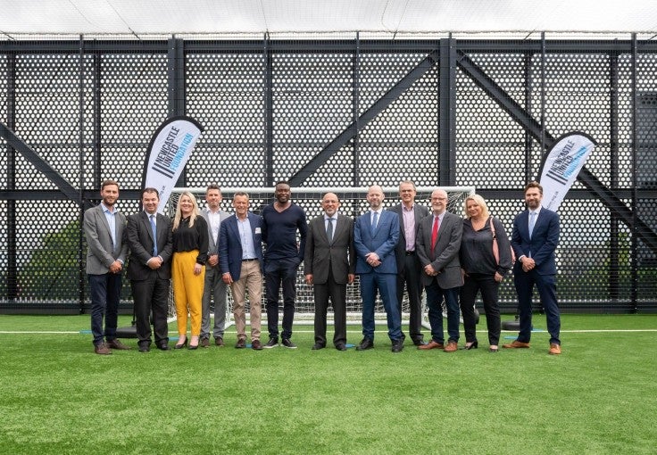 A group of Newcastle Foundation members and supports standing in front of a goal at the new NUCASTLE building.