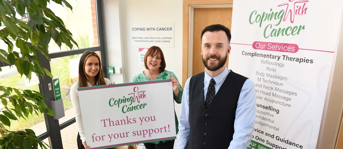 Three people holding a coping with cancer banner