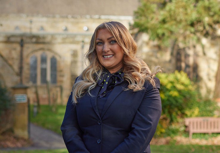 Ponteland's Branch Manager, Natalie, stood smiling in front of a church in Ponteland. 