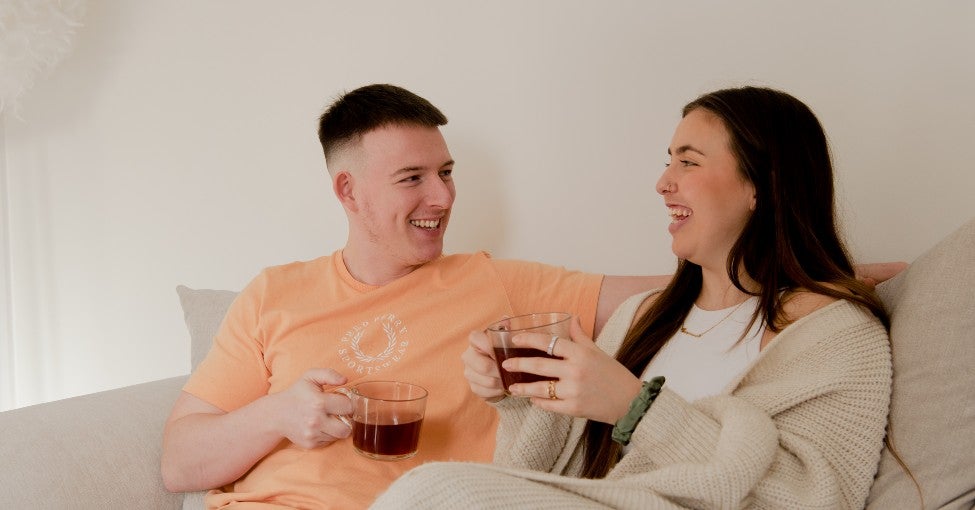 Couple sat on a sofa drinking coffee