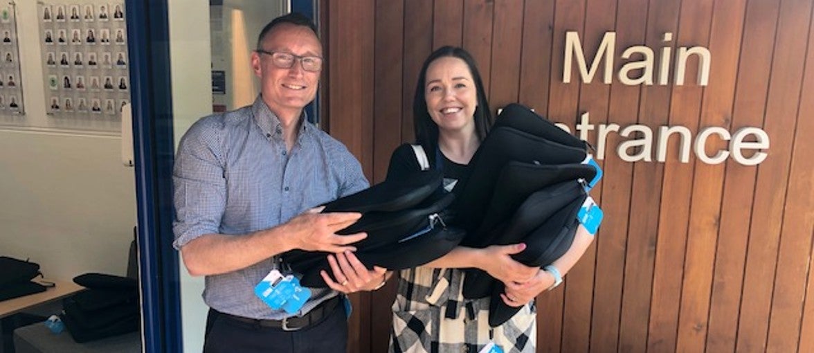 A man and a lady holding donated chromebooks