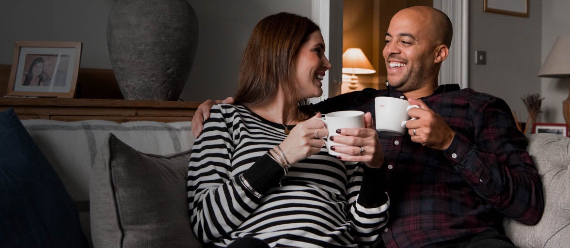 Man and woman having a cup of coffee on the sofa.
