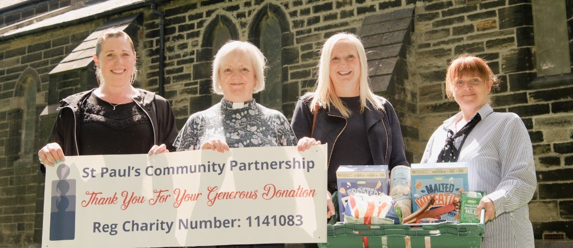 A group of ladies stand outside a church with a St Paul's Community Partnership banner.