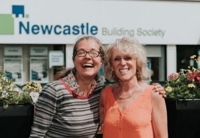 Two women laugh and hug outside a branch