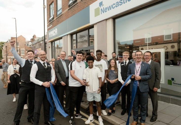 A group of Newcastle Building Society colleagues and members of YMCA North Tyneside stood outside of the YMCA North Tyneside building, getting ready for a ribbon cutting.