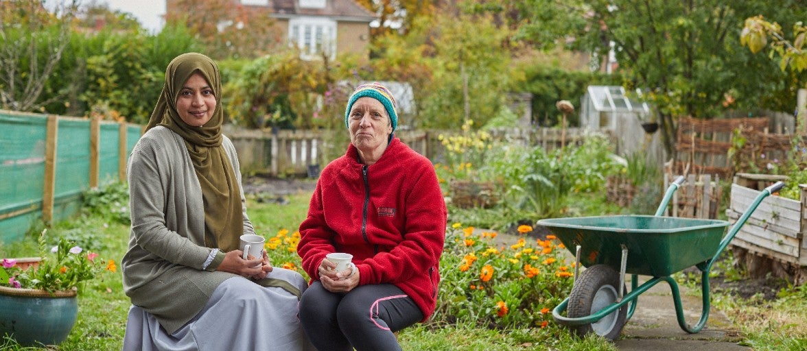 Two ladies sitting outside in a garden with a cup of tea
