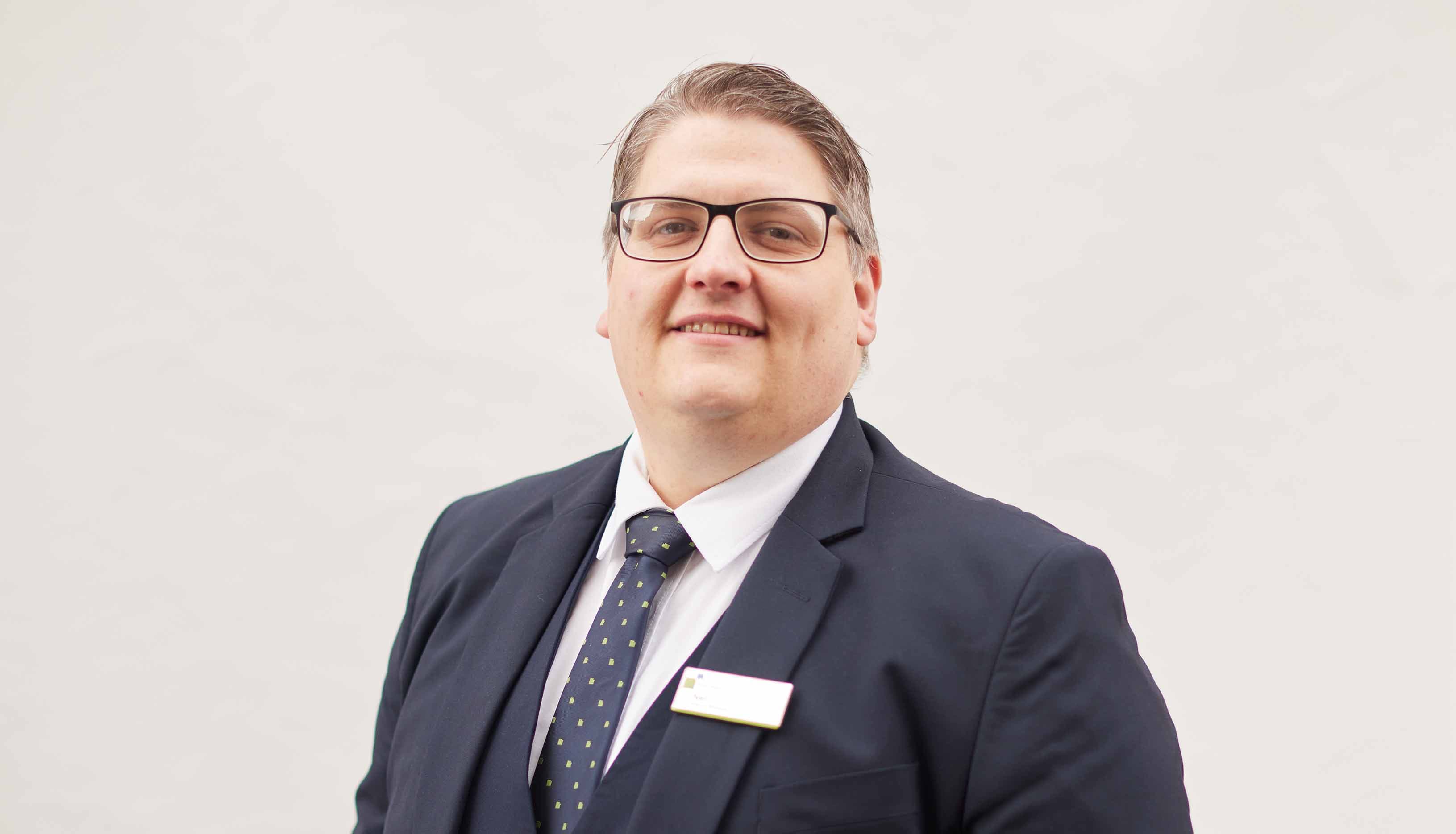 Whitely Bay's Branch Manager, Neil, stood with a white background smiling. 