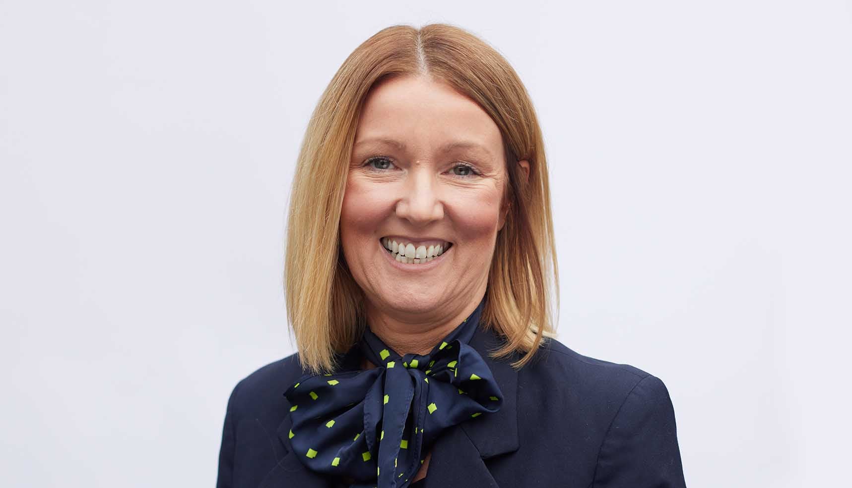 Yarm's Branch Manager, Bev. Smiling in front of a white background. 