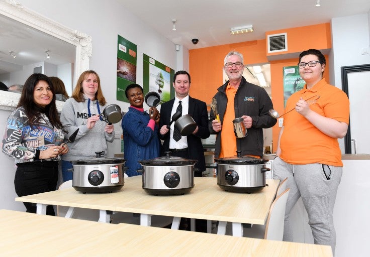 A group of people with slow cookers and kitchen equipment.