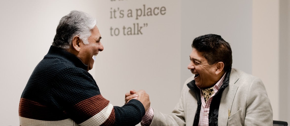 Two men shaking hands and laughing.