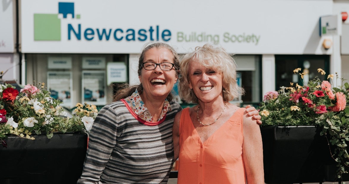Two smiling women standing outside a Newcastle Building Society branch
