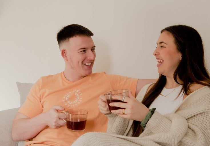 Couple sat on the sofa drinking coffee