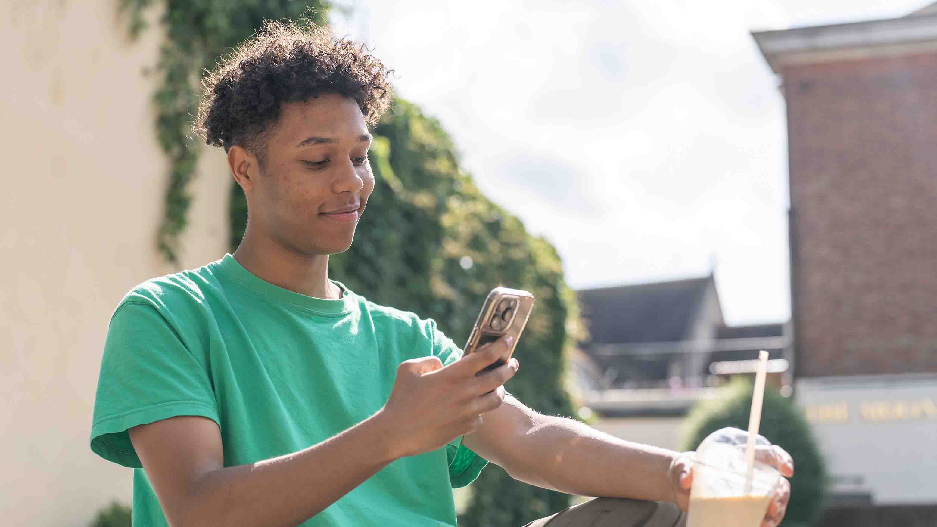 Young man outside using his mobile phone, smiling. 