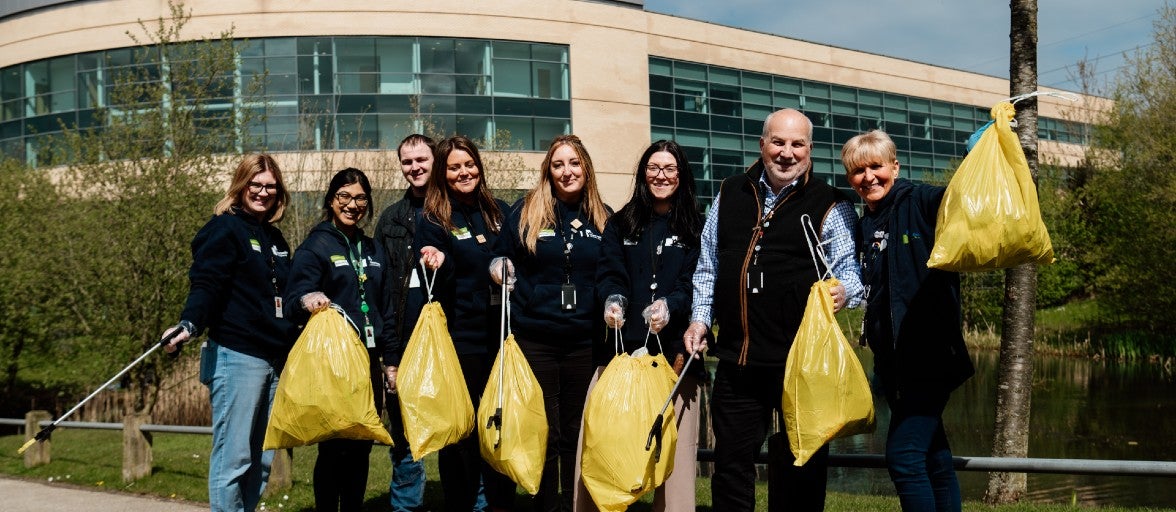 Colleagues posing with litterpickers and bin bags outside of Newcastle Building Society's head office.