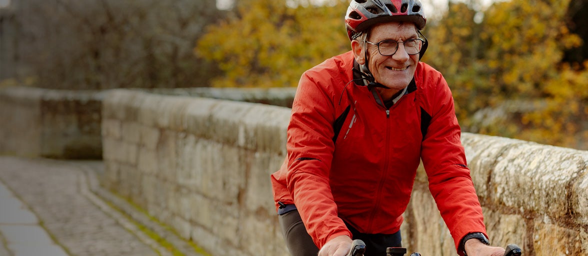 Man smiling riding a bicycle across a bridge