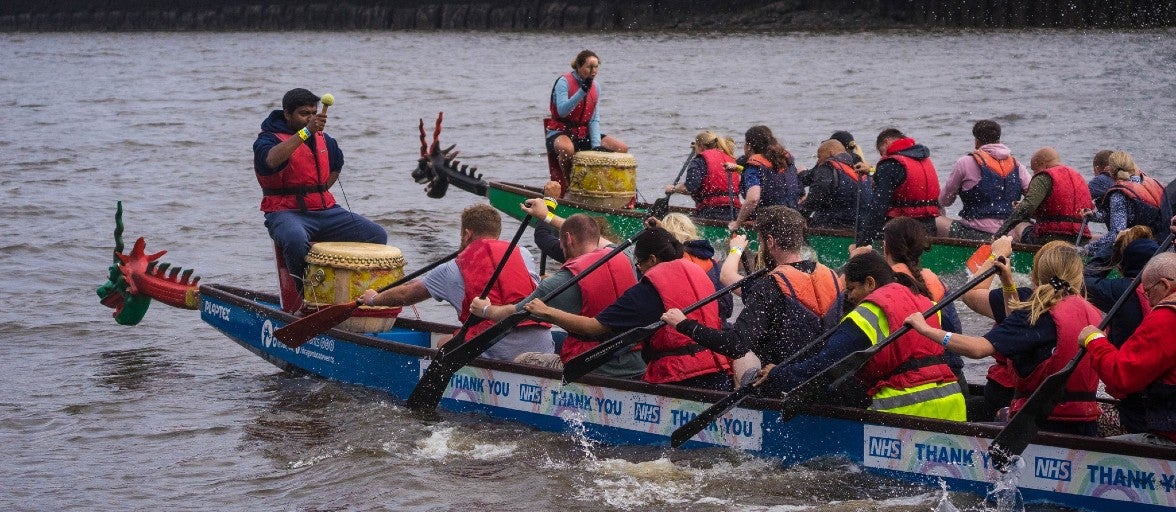 Two groups of people racing against each other in dragon boats on the River Tyne. The boat in the foreground contains Newcastle Building Society colleagues.