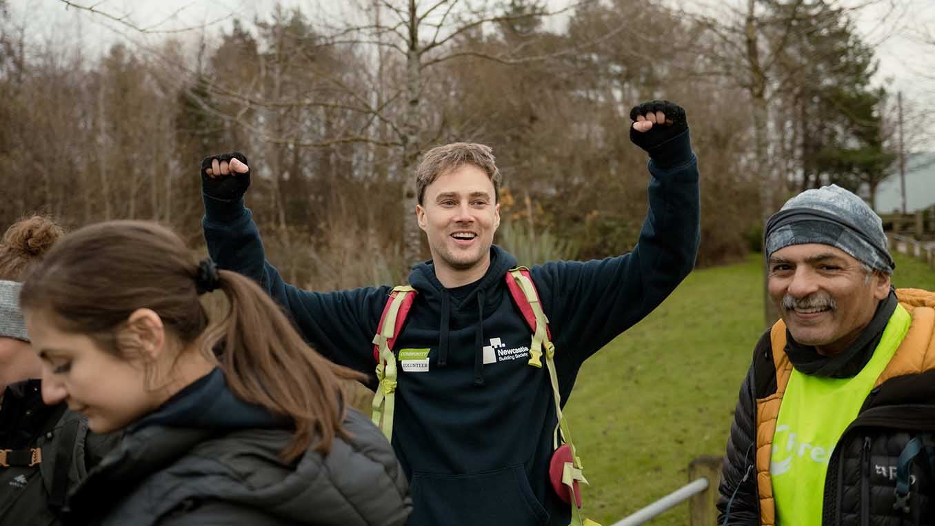 Newcastle Building Society colleagues on a charity hike, with Sean raising his arms in the air smiling. 