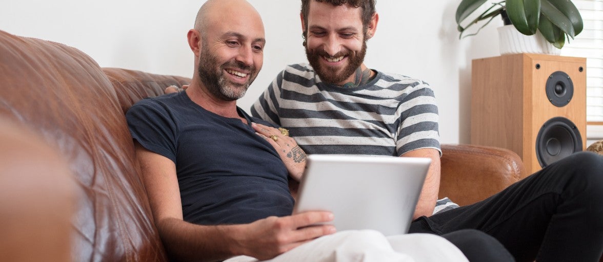 Two men smiling at a tablet screen