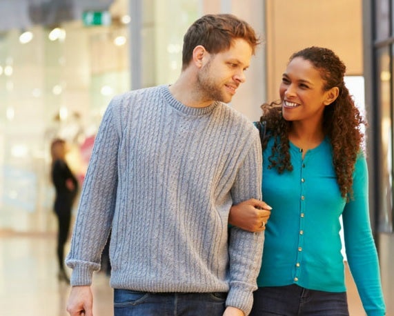 A young couple linking arms and shopping
