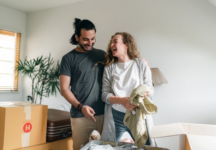 A couple laugh as they unpack boxes in their new home
