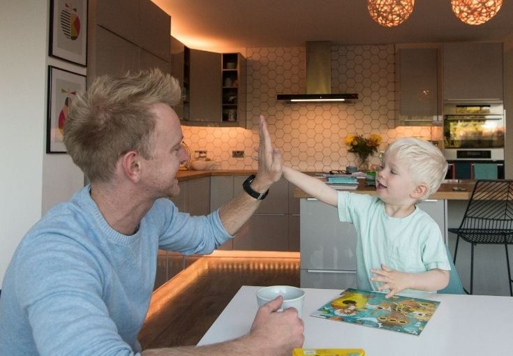 Dad and son giving a high five at the dinner table