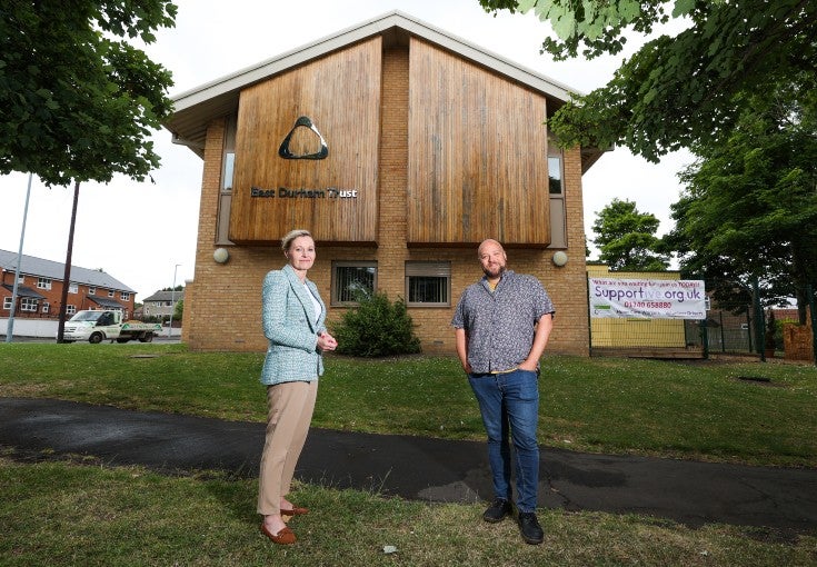 Two people stand outside the East Durham Trust