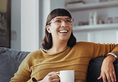 A happy woman relaxing on a sofa while having a cup of coffee