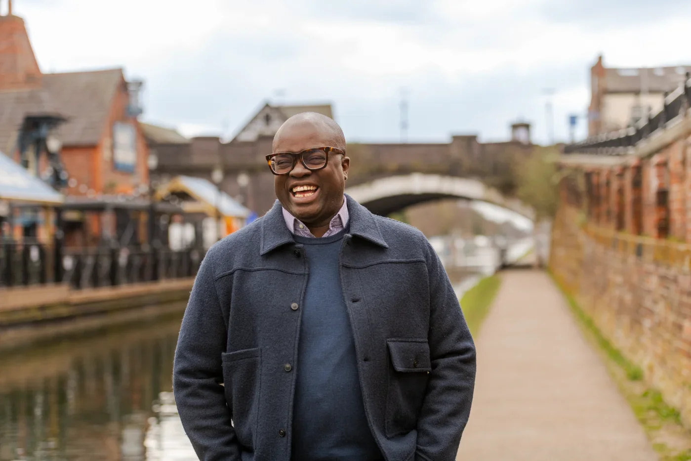 A man smiling at the camera by a canal in Trafford.