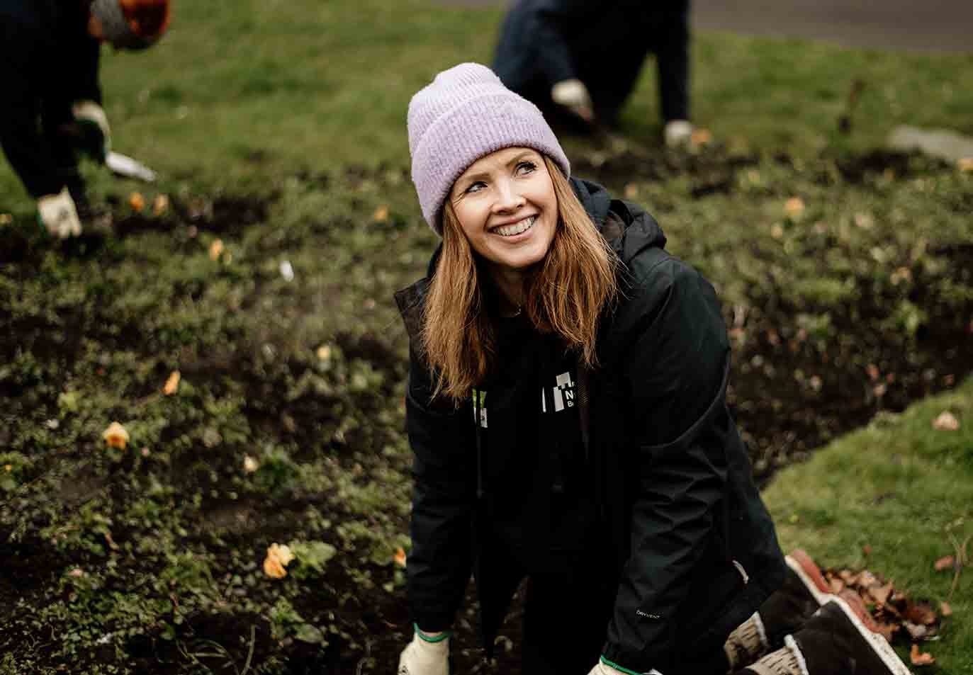 A Newcastle Building Society employee volunteering, gardening in a park. 