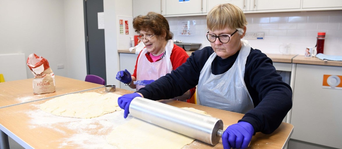 Two members of Yatton House rolling some dough to make cookies.