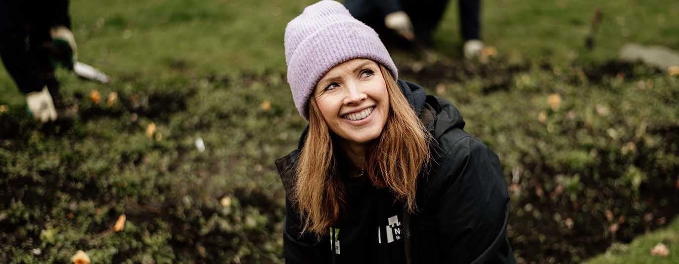 A woman wearing a purple beanie volunteering 