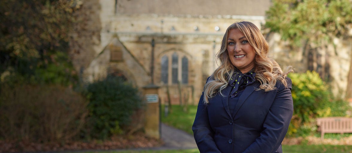 Ponteland's Branch Manager, Natalie. Stood in front of a church in Ponteland, smiling. 
