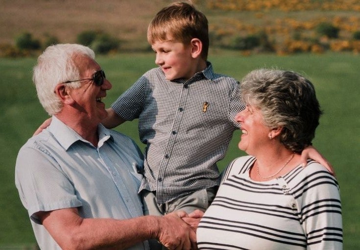 An elderly couple hold their grandson
