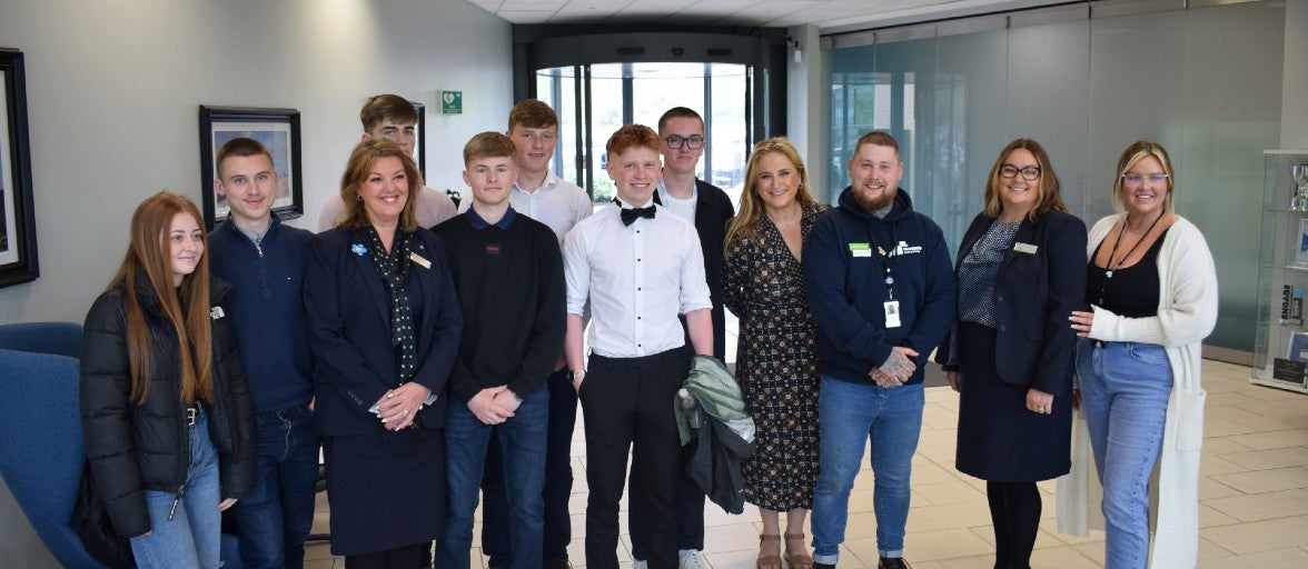 A group of students and office workers posing for a photo in the main reception of an office.