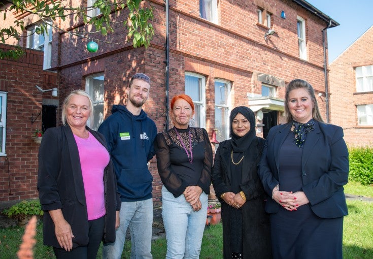 Two Newcastle Building Society colleagues stood with colleagues from the Parker Trust outside one of their buildings.