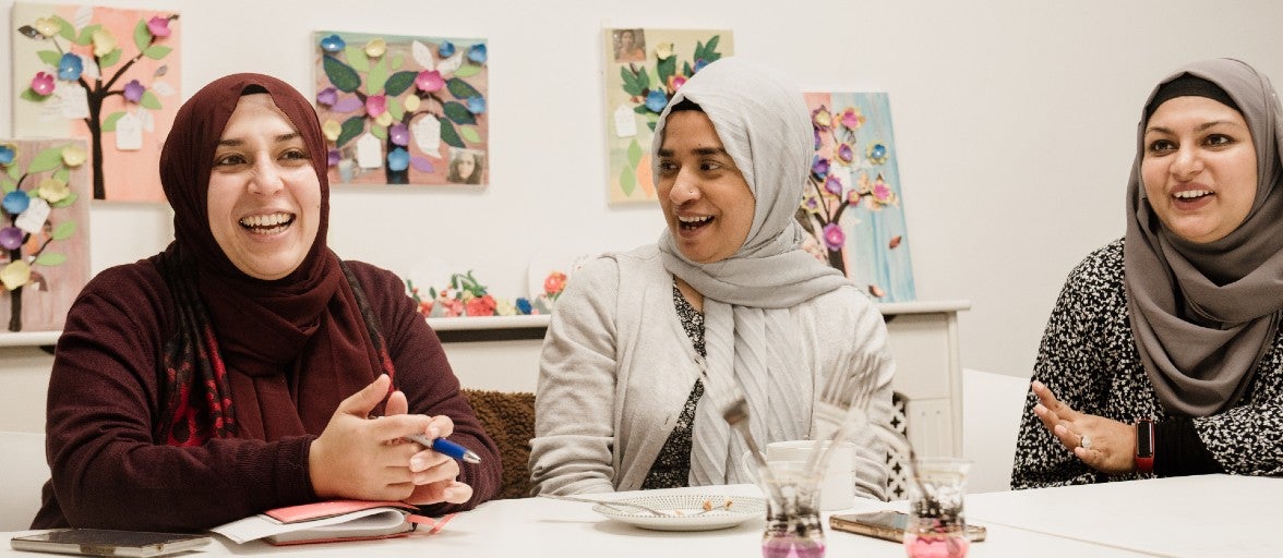 Three ladies chatting and laughing with each other at Apna Ghar.