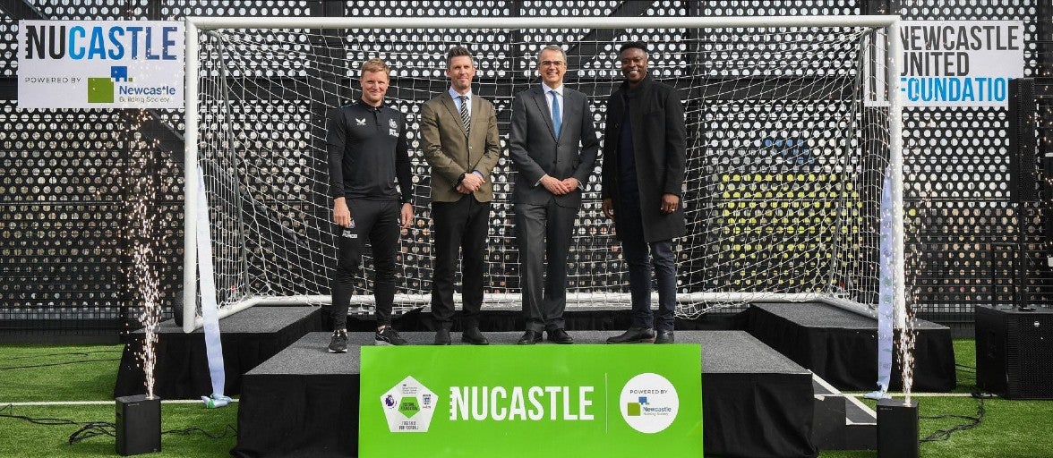 A group of people including Shola Ameobi and Andrew Haigh standing in the goal at the new NUCASTLE building.
