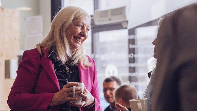 A woman holding a mug and smiling