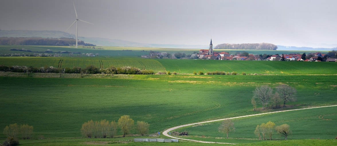 Landscape photo with a wind turbine in the distance and a small village.