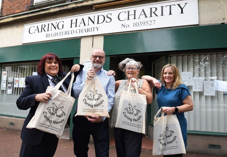Four people with Caring Hands tote bags.