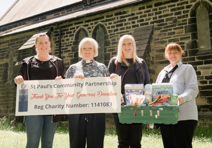 A group of ladies stand outside a church with a St Paul's Community Partnership banner.