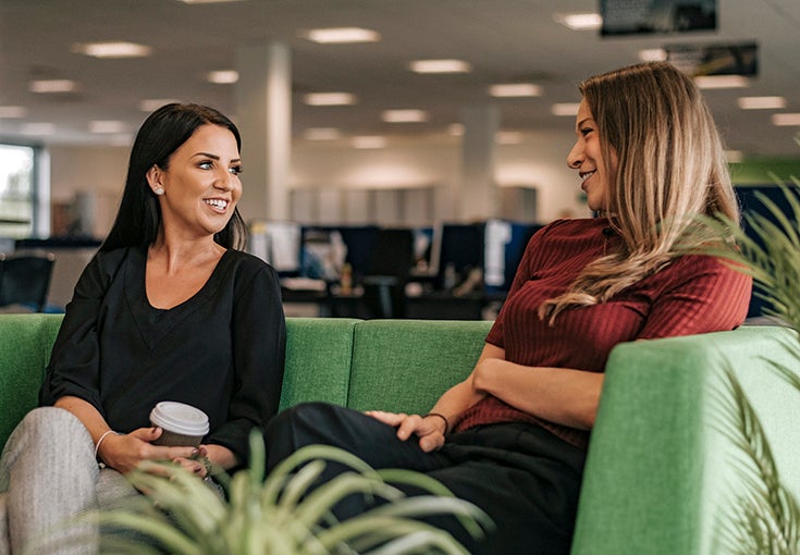 Two women chat on a sofa