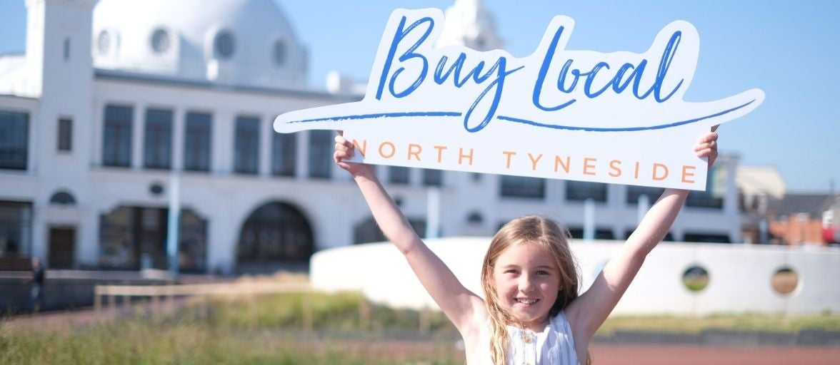 A child with the Buy Local North Tyneside sign outside Spanish City, Whitley Bay