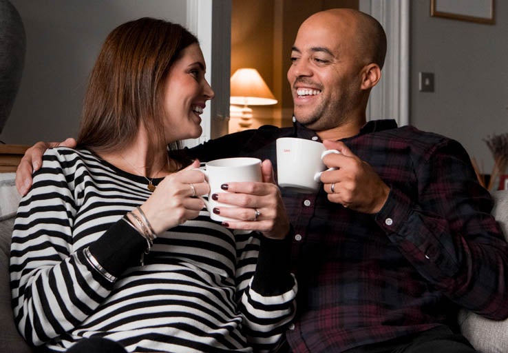 Man and woman having a cup of coffee on the sofa.