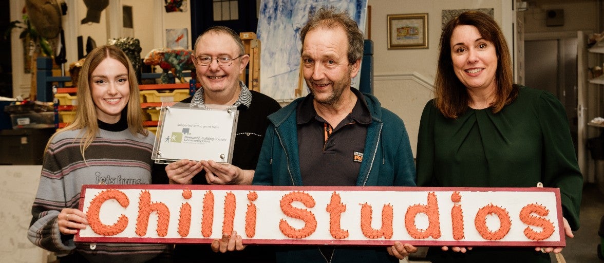 Members of Chilli Studios and our Head of Group Communications, Kathryn McLaughlin, holding a 'Chilli Studios' sign and smiling for the camera.