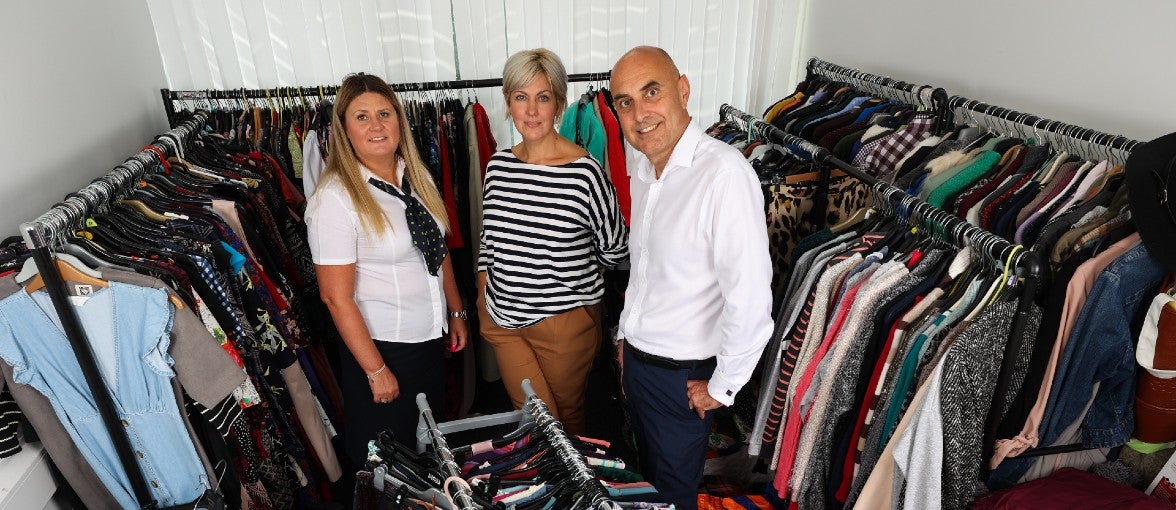 Three people amongst the clothing rails at Age UK Teesside.