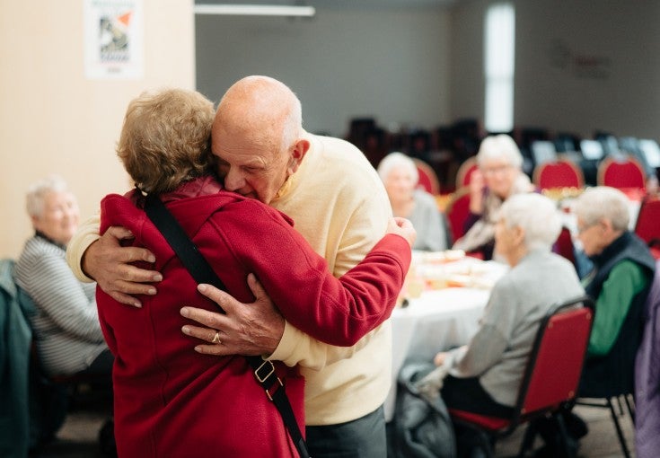 Two Mind Active service users hugging at their Christmas lunch club event